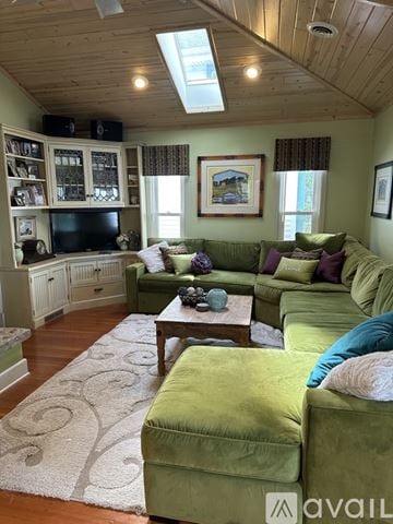 Lake Mills house for rent - A living room with green couches and a wooden ceiling.