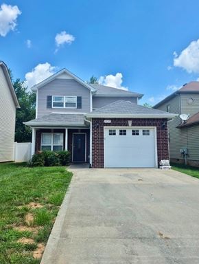 Clarksville house for rent - A two-story house with a garage door is in front of a white fence.