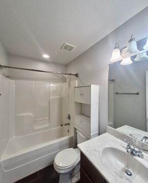 Clarksville house for rent - A white toilet sits next to a white sink in a small bathroom.