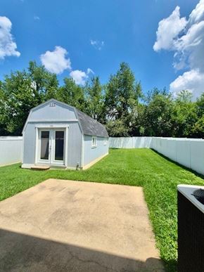 Clarksville house for rent - A small blue building with a white door and a window is surrounded by a white fence and green grass.