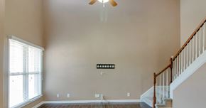 Clarksville house for rent - A living room with a staircase and a ceiling fan.