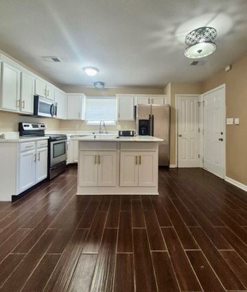 Clarksville house for rent - A kitchen with white cabinets and a brown floor.
