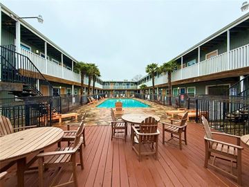 Austin apartment for rent - A wooden deck with chairs and a pool in the middle of it.