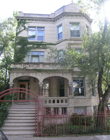 Chicago apartment for rent - A large, old building with a red gate in front.
