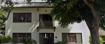 Anaheim apartment for rent - A white two-story house with a balcony on the second floor.