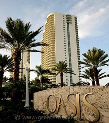 Fort Myers apartment for rent - A tall white building with the word Oasis written on a stone wall in front of it.