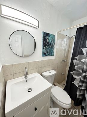Miami apartment for rent - A bathroom with a toilet, sink, mirror and shower.