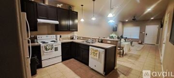 Three Rivers townhouse for rent - A kitchen with a white stove top oven and black cabinets.