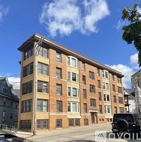 Madison apartment for rent - A large brick building with many windows is in the foreground.