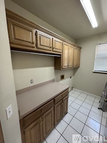 Warr Acres house for rent - A kitchen with wooden cabinets and white tiled flooring.