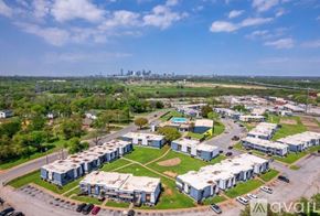 Dallas apartment for rent - A large building complex with a parking lot in front and a city skyline in the distance.