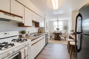 Scranton apartment for rent - A modern kitchen with a black refrigerator, white cabinets, and a dining area with a table and chairs.