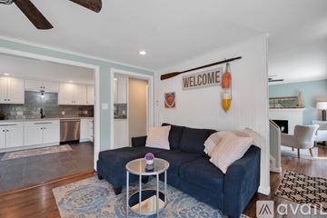 Old Saybrook house for rent - A living room with a blue couch and a white wall with a "Welcome" sign.