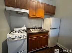 Chicago apartment for rent - A kitchen with a white gas stove, a white refrigerator, and wooden cabinets.