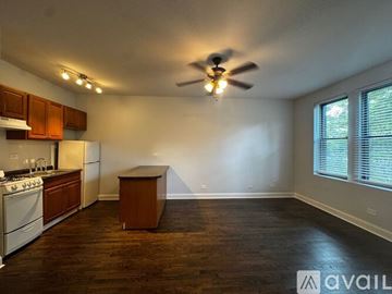 Chicago apartment for rent - A kitchen with a white stove top oven and a white refrigerator with wooden cabinets.