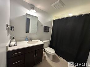 Chicago apartment for rent - A white bathtub with a black shower curtain and a silver faucet.