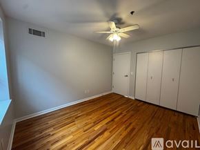 Chicago apartment for rent - A room with wooden floors and white walls, featuring a ceiling fan and a window.