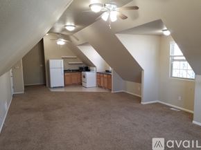 Pueblo apartment for rent - A spacious room with a carpeted floor and a ceiling fan.