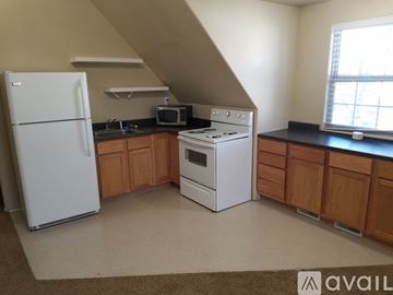 Pueblo apartment for rent - A kitchen with a white fridge, white stove and wooden cabinets.