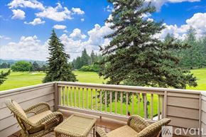 Bigfork townhouse for rent - A balcony with wicker chairs and a table overlooks a grassy field.