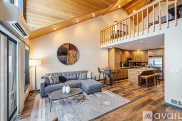 Bigfork townhouse for rent - A modern living room with a grey sofa and a round mirror on the wall.