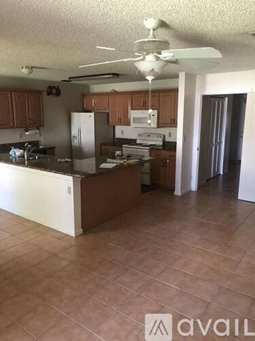 Royal Palm Beach house for rent - A kitchen with brown cabinets and a white refrigerator.