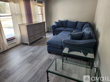 Mesick apartment for rent - A living room with a blue couch and a glass coffee table.