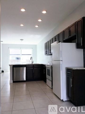 Poinciana apartment for rent - A kitchen with black cabinets and a white refrigerator.