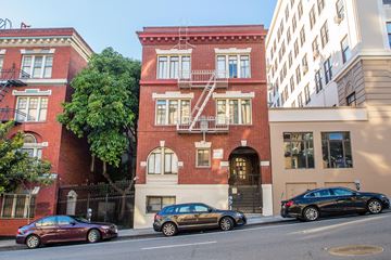 San Francisco apartment for rent - A red brick building with a black car parked in front.