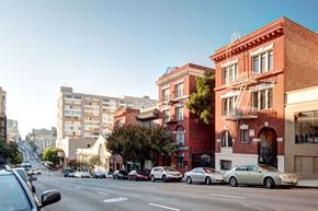 San Francisco apartment for rent - Cars are driving on a street with buildings on both sides.