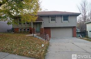 Omaha house for rent - A house with a garage and a driveway covered in fallen leaves.