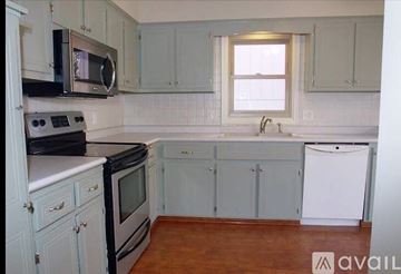 Omaha house for rent - A kitchen with white cabinets and a black stove top oven.
