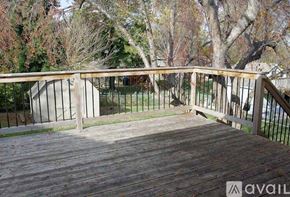 Omaha house for rent - A wooden deck with a metal railing and trees in the background.