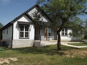 Granite Shoals house for rent - A small white house with a black roof and a tree in front.