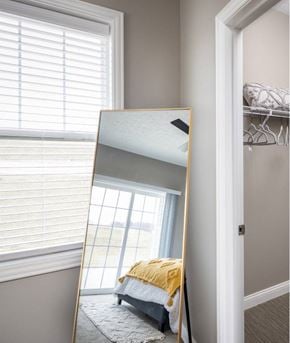 Canton apartment for rent - A large mirror reflects a bedroom with a bed and a window.