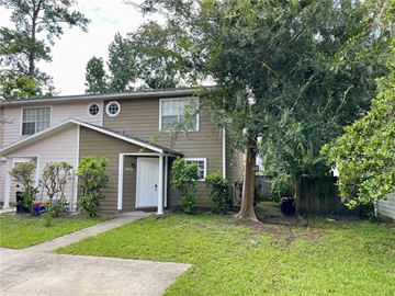 Gainesville house for rent - A house with a brown and beige exterior is surrounded by greenery.