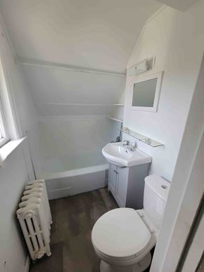 New Glasgow apartment for rent - A white toilet sits in a small bathroom with a white sink and a white cabinet.