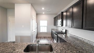 Forney house for rent - A kitchen with dark wood cabinets and a granite countertop.