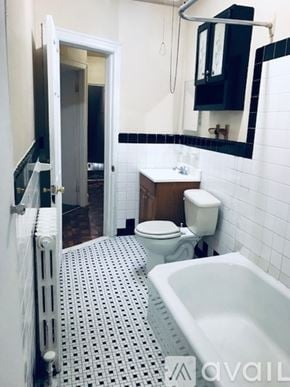 Trenton apartment for rent - A white toilet sits in a bathroom with a white bathtub and a white sink.