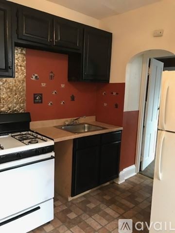 Trenton apartment for rent - A kitchen with black cabinets and a white stove top oven.