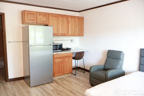 Elroy apartment for rent - A kitchen with a refrigerator, a chair, and a bed.