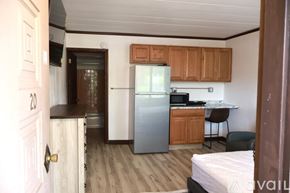 Elroy apartment for rent - A small room with a bed, desk, and refrigerator.