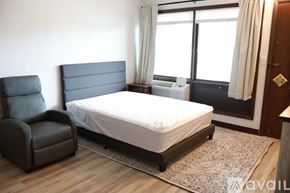 Elroy apartment for rent - A bedroom with a large bed, a chair, and a window.