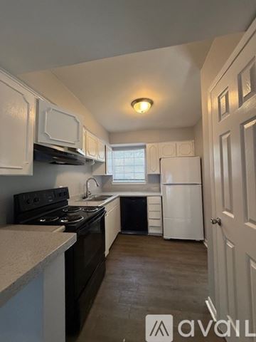 Bryan apartment for rent - A kitchen with white cabinets and black appliances.