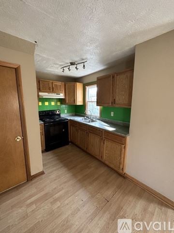Canton house for rent - A kitchen with wooden cabinets and a black stove top oven.
