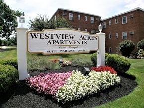 Parma apartment for rent - A sign for Westview Acres Apartments with a flower bed in front.