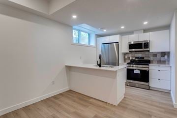Edmonton apartment for rent - A kitchen with white cabinets and a wooden floor.