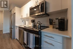 Oshawa (O'neill) condo for rent - A modern kitchen with a black stove top oven and white cabinets.
