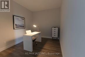 Oshawa (O'neill) condo for rent - A white desk with a chair and a lamp in a room with a framed picture on the wall.