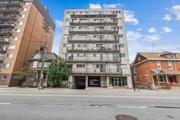 Ottawa apartment for rent - A street view with apartment buildings and a blue sky with clouds.